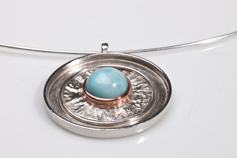 Zilveren hanger met gehamerde structuur en een lichtblauwe larimar steen