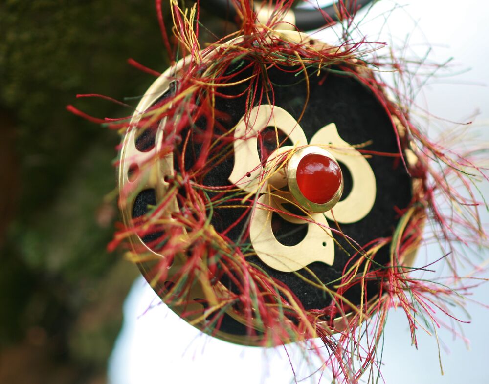 Ronde broche in messing met een rode agaat en decoratieve draden